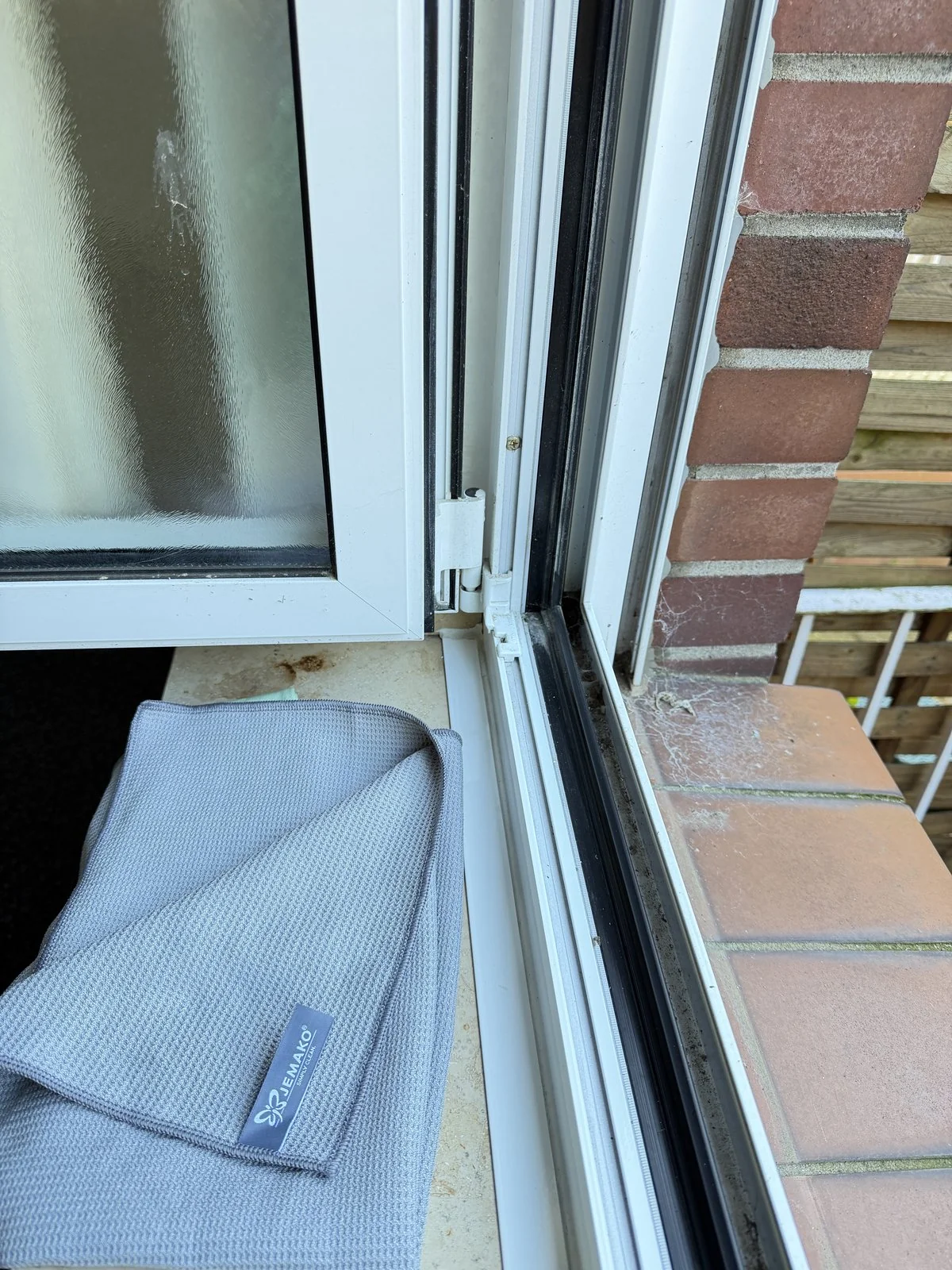 Verschmutzte Fensterecke mit Belag auf Rahmen und Glas vor der Reinigung in Grevenbroich – Sicht durch das Fenster eingetrübt